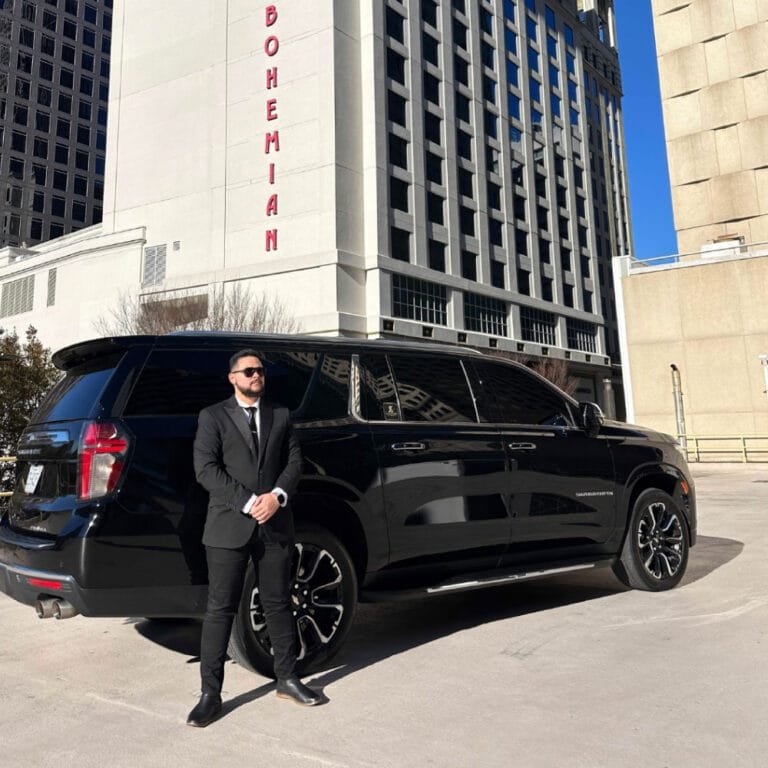 Chauffeur beside a black SUV in front of a hotel