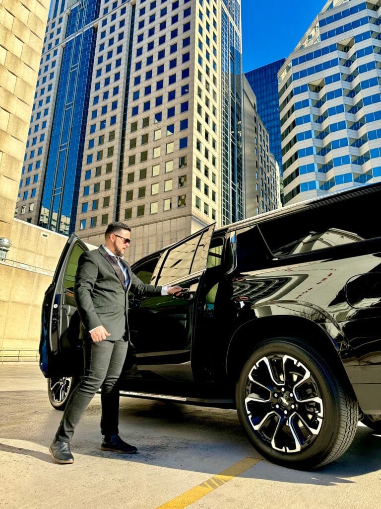 Chauffeur opening the door of a black SUV in uptown Charlotte