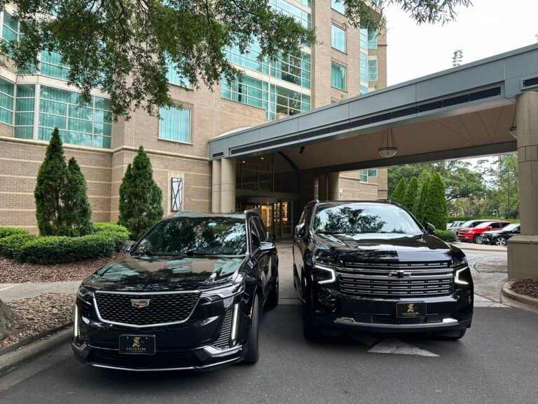 Black Cadillac sedan and SUV at a hotel entrance