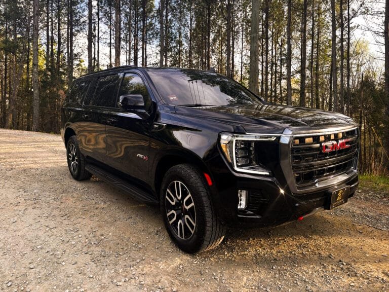 Black GMC SUV parked among pine trees