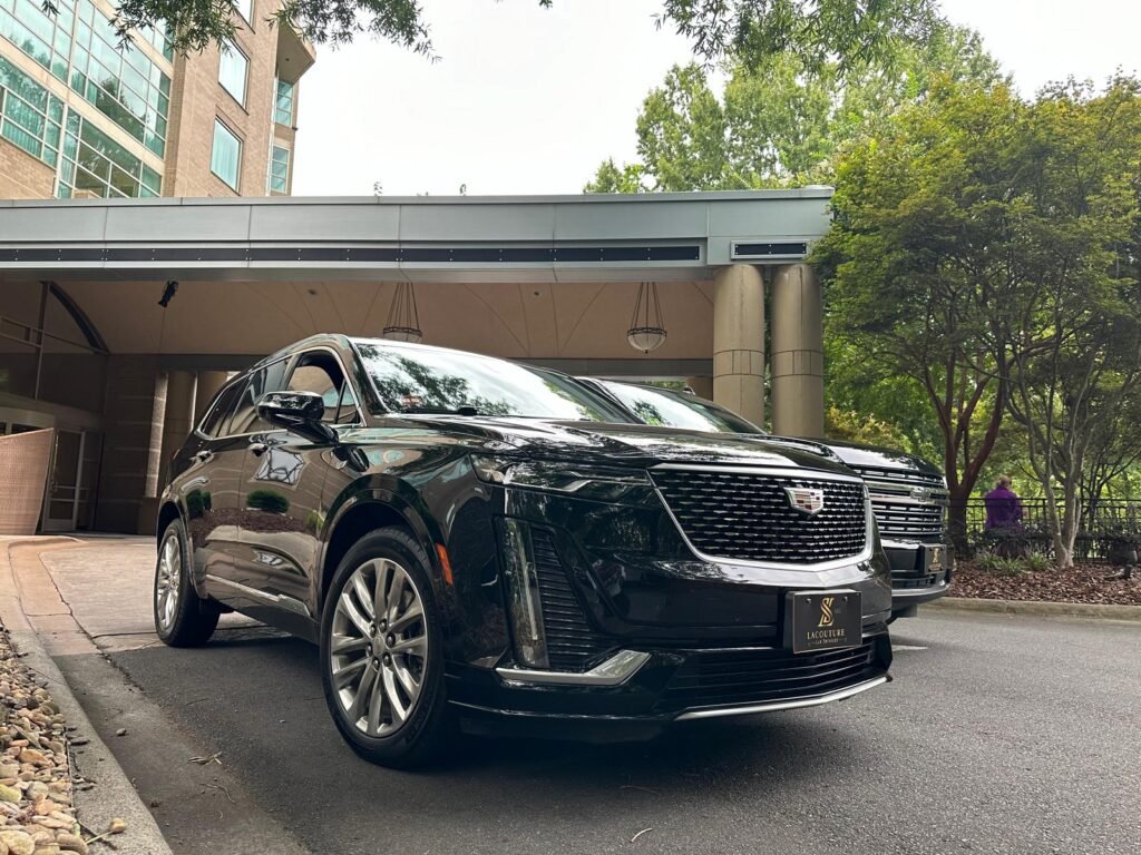 Black Cadillac executive vehicle at a Charlotte hotel entrance, Lacouture Lux Services